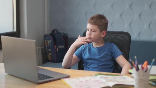 Portret van een jongen die online lessen geeft op afstand via laptop en internet via videochat. Afstandsonderwijs thuis. — Stockvideo