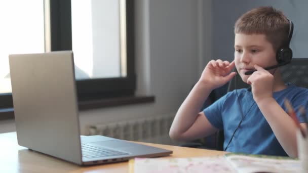 Retrato de um menino ensinando aulas on-line à distância usando laptop e internet via vídeo chat. Ensino à distância em casa. — Vídeo de Stock