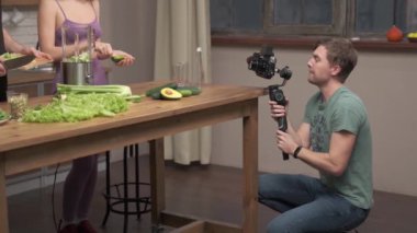 Kameraman mutfak sahnesini çekiyor. Aşık çift evde sağlıklı yemek hazırlıyor.