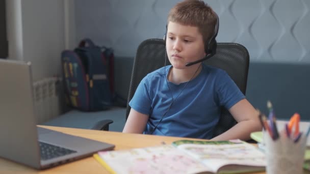 Un petit garçon intelligent utilise l'ordinateur pour discuter en vidéo avec son professeur. E-éducation enseignement à distance, enseignement à domicile, covid. Éducation apprentissage en ligne, Les élèves adolescents portent un casque — Video