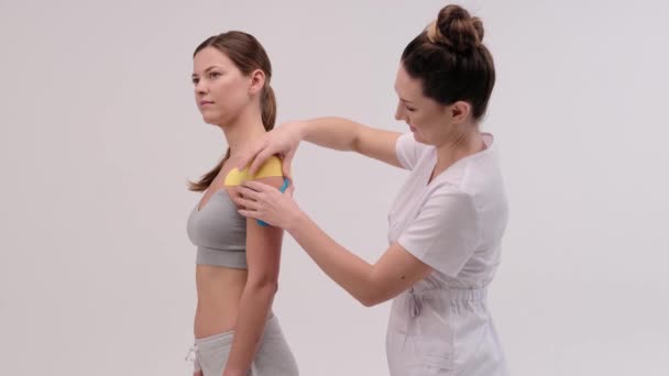 치료가는 여성의 몸에 방추사 테이프를 적용하고 있습니다. 물리 요법 과 동역학 개념. — 비디오