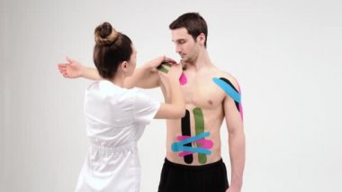 Kinesio bandıyla omuz tedavisi. Fizyoterapist hastanın omuz yaralanmasına elastik tedavi bandı uyguluyor. 4 bin. Hafif arkaplan