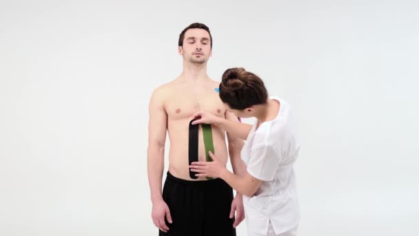 Female Therapist Applying Kinesiology Tape Man Abdomen Light Background Woman — Stock Video