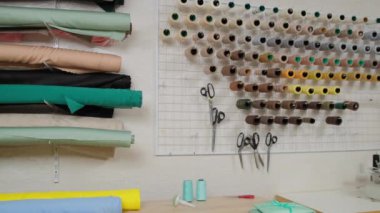 Terzi atölyesi, terzilik siparişi. Küçük bir moda stüdyosunun içinde. Kumaş ruloları, iplik makaraları ve desenler. Küçük işletme