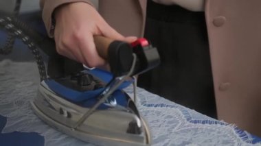 Siview, terzi kadın buharlı danteli, atölyedeki ütü masasında dikmeye hazırlarken orta derece yatır. profesyonel demir buharlı gemi