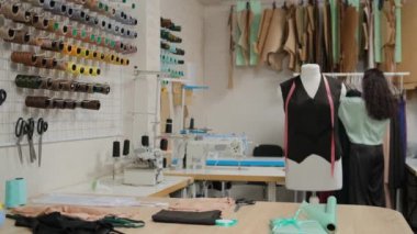 Terzinin atölyesi. Elbiseleri askıya asmak. Aptal, askı arka planında terzinin üstünde duruyor. Küçük işletme