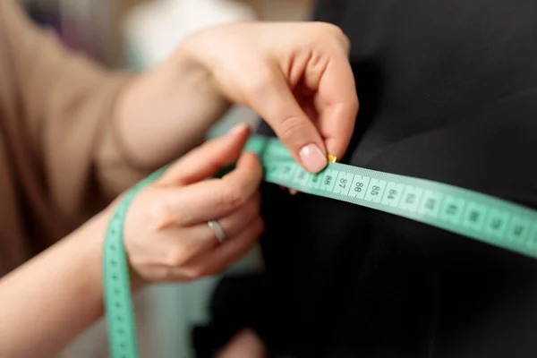 A centimeter is a tailor\'s tool for measuring when sewing. A centimeter is a tool for measuring dimensions. A meter for sewing clothes. Tailoring for the tailor. Human hands. Close up