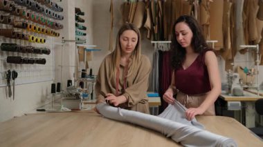 Atölyede kumaşı açan iki terzi. Moda tasarımcıları ya da terziler sırayla çalışıyor..