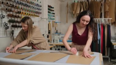 Masada tebeşir ve bezle çalışan iki terzi. Kadın terzi atölyedeki tekstil deseninde tebeşir kullanıyor. Profesyonel terzi, dikiş stüdyosunda moda tasarımcısı..