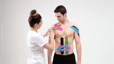 Kinesio bandıyla omuz tedavisi. Omuz yaralanmasına elastik tedavi bandı uygulayan fizyoterapist.