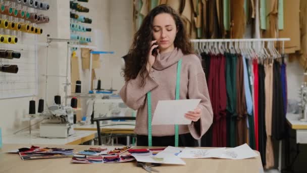 成功したテイラー起業家は携帯電話で話しています。女性は繊維サプライヤーから生地を注文忙しいです。服のデザインスタートアップコンセプト. — ストック動画