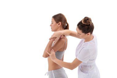 Doktor fizyoterapist beyaz arka planda izole edilmiş genç bir spor kadınını geriyor.