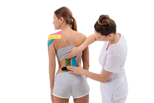 理疗师在女性患者腰背下部应用运动学磁带。运动学、物理治疗、康复概念. — 图库照片