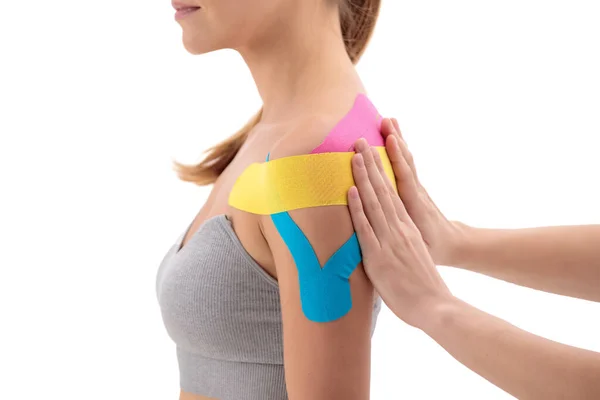 理疗师在女性患者身上贴上动感胶带 肩负着白色背景隔离的肩带 靠近点 — 图库照片