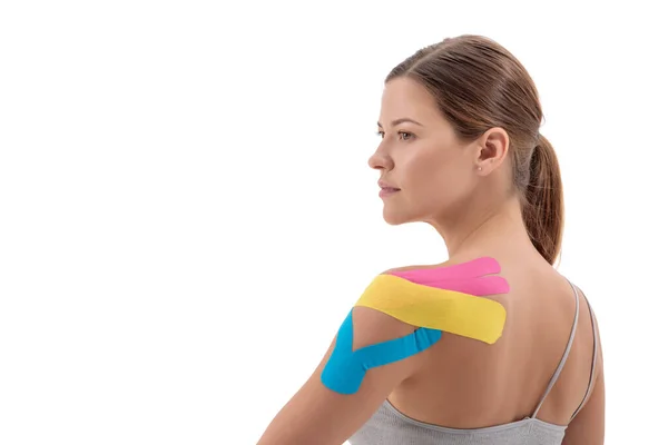 年轻女运动员肩上的彩色运动疗法带 白色背景隔离 左边的复制空间 — 图库照片
