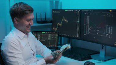 Bir borsa grafiğini analiz eden bir işadamı. Genç erkek işadamı döviz borsasından para kazanıyor. Büyük ekranlarda diyagramlar