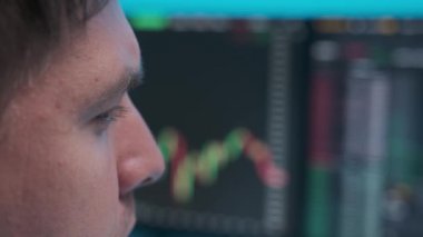 Monitörlerdeki ticaret takvimine bakan genç bir iş adamının yakın plan yüzü..