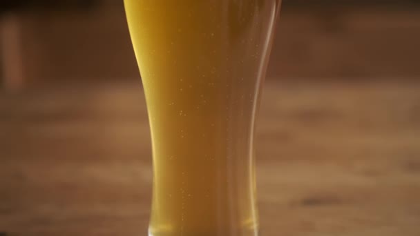 Пиво. Холодное светлое пиво в стакане с каплями воды. Пинта пива на деревянном фоне. — стоковое видео