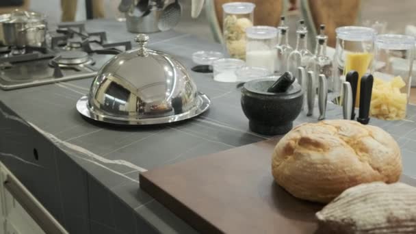 Vue de la table de cuisine avec du pain frais et un plat recouvert d'un couvercle métallique — Video