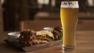 Taze bira aperatifleri çeşitli ve bir bardak bira. Kafede bir tabak bira. Bulanık arkaplan