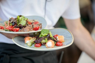 Garson salata tabakları taşıyor.