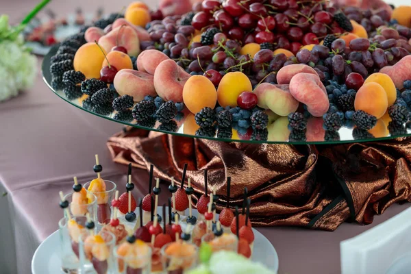 Mesa com uma variedade de lanches de frutas e bagas. Buffet para uma sobremesa da empresa. Cerejas frescas, morangos, damascos — Fotografia de Stock