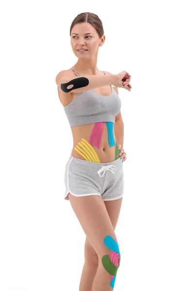 Mujer mostrando cintas de kinesio pegadas a su cuerpo. Retrato completo de mujer con cintas de kinesio médicas brillantes —  Fotos de Stock