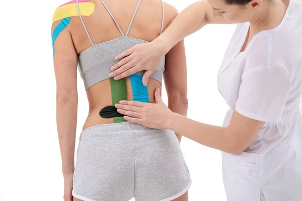 Fisioterapeuta aplicando cinta de kinesio a pacientes femeninas de la espalda baja. Kinesiología, fisioterapia, concepto de rehabilitación. de cerca — Foto de Stock
