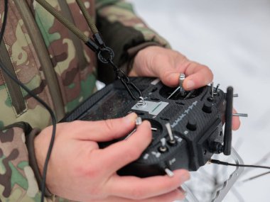 Askeri operatör FPV İHA 'yı kontrol etmek için RC kullanıyor ve düşman mevzilerine mayın ve el bombası atmak için cihaz kullanıyor. FPV insansız hava aracından uzaktan kumanda tutan asker