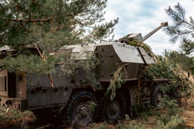 Kamuflajlı Topçu Pozisyonu Suzanne, topçu teçhizatını ormana yerleştirdi. Askeri araç dallarla kamufle edilmiş.