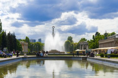 Kyiv, Ukrayna - 05.11.2025: Bulutlu bir gökyüzünün altındaki bir şehir parkındaki büyük bir su çeşmesinin manzarası. Görkemli mimarisi ve yeşil ağaçlarıyla kamusal alanda dinlenen insanlar.