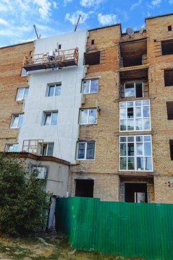 Hasarlı tuğla bina yenileniyor. Yeni pencereler ve cephe yalıtımı var. İnşaat beşiği kullanılıyor.