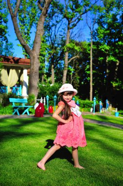 Beyaz şapka ayakta çimenlerin üzerinde küçük kız