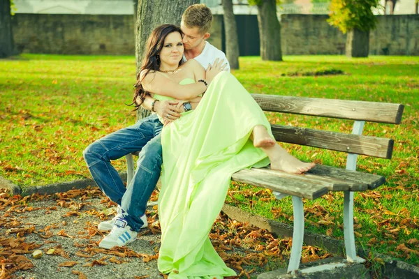 Attractive the guy with the girl sit and embrace on a bench — Stock Photo, Image