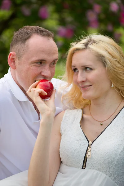 Preciosa pareja mordiendo manzana en el picnic —  Fotos de Stock