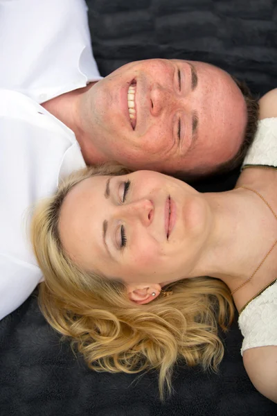 Szczęśliwa i uśmiechnięta para z zamkniętymi oczami leży na gray plaid — Zdjęcie stockowe