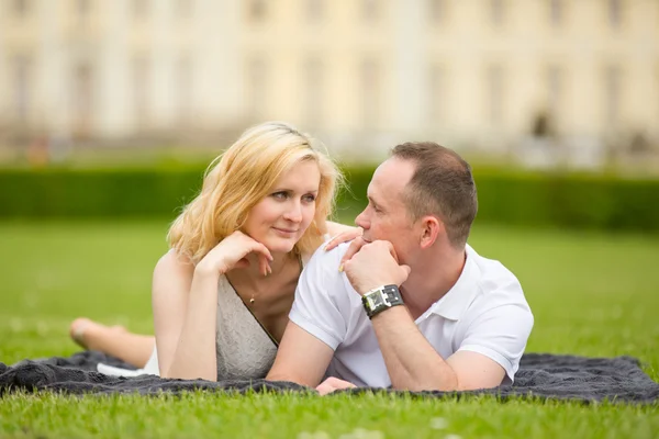Młoda, szczęśliwa i uśmiechnięta para leży na trawie — Zdjęcie stockowe