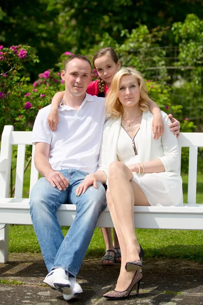 Famiglia felice si siede su una panchina nel parco all'aperto — Foto Stock