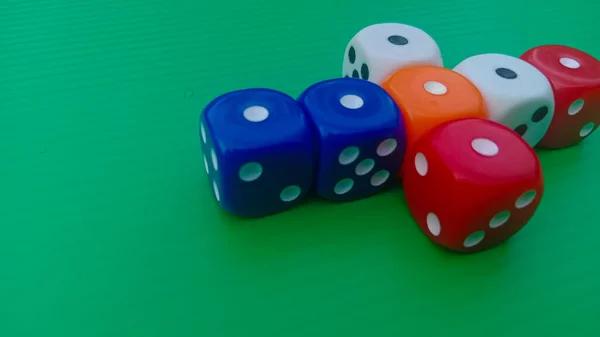Pair of colorful dice placed on a bright green background.