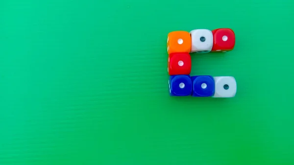 Pair of colorful dice placed on a bright green background.