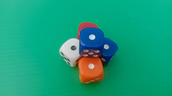 Pair of colorful dice placed on a bright green background.