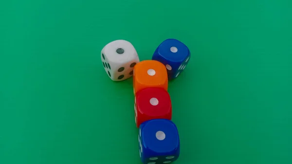 Pair of colorful dice placed on a bright green background.