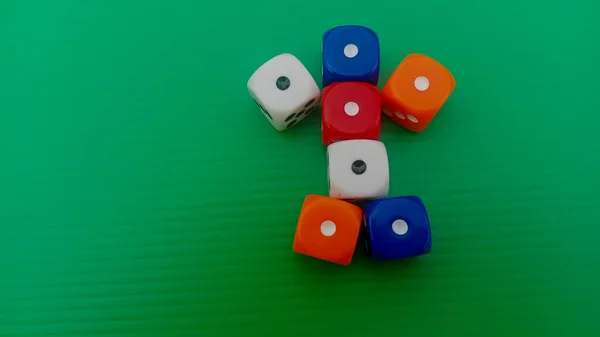 Pair of colorful dice placed on a bright green background.