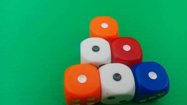 Pair of colorful dice placed on a bright green background.