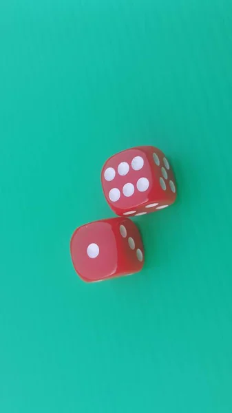 Pair of colorful dice placed on a bright green background.
