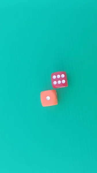 Pair of colorful dice placed on a bright green background.