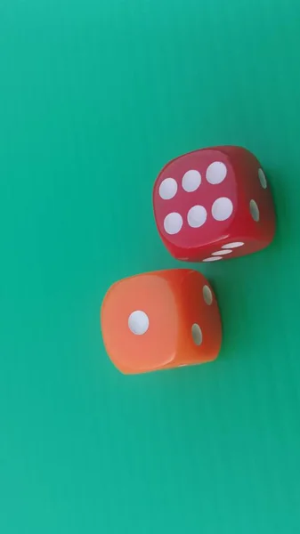 Pair of colorful dice placed on a bright green background.