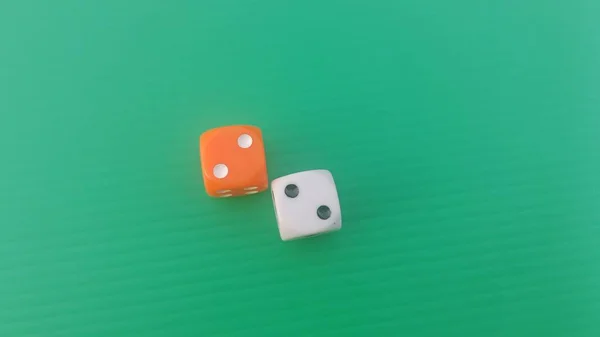Pair of colorful dice placed on a bright green background.
