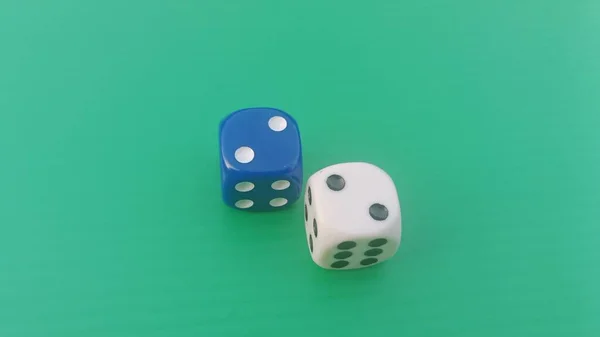Pair of colorful dice placed on a bright green background.