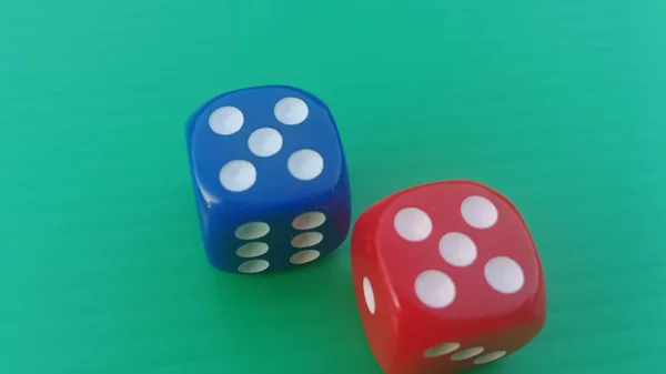 Pair of colorful dice placed on a bright green background.